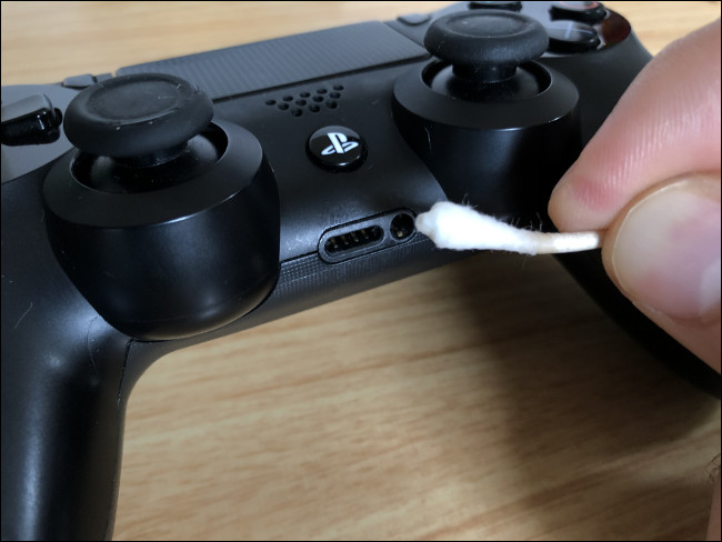 A Q-tip cleaning a port on a DualShock 4 Controller.