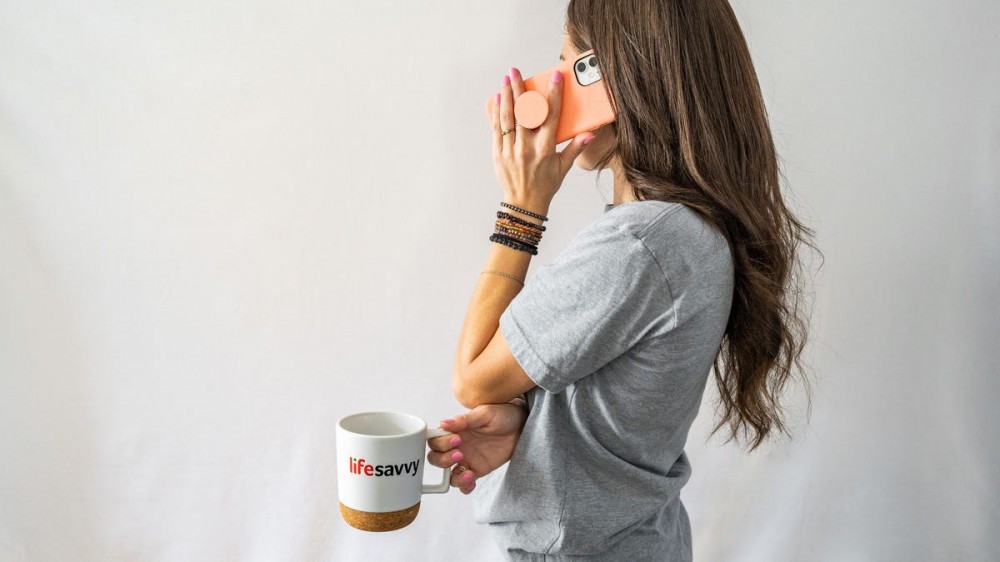 A young woman holds an iphone in a special iphone case with a grip to talk on the phone.