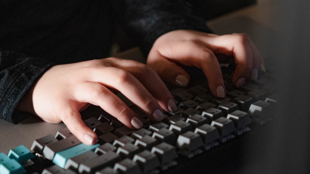 Person typing ominously on a dark keyboard